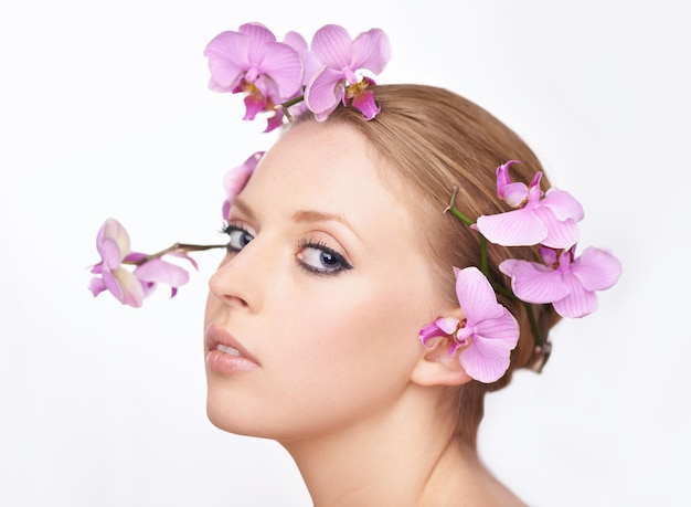 Belleza juvenil en plena floración Retrato de estudio de una hermosa mujer joven con orquídeas rosas en el pelo