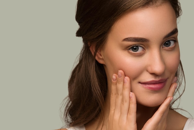 Belleza mujer cara piel sana cuidado mujer hermosa mujer Tocando su rostro. Fondo de color verde