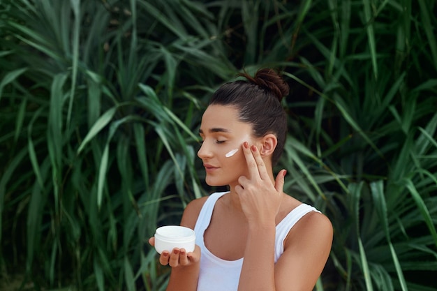 Belleza Mujer Concepto Cuidado de la piel Retrato de modelo femenino aplicando crema hidratante cosmética