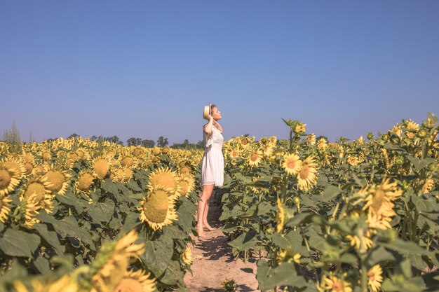 Belleza mujer iluminada por el sol en el campo de girasol amarillo Concepto de libertad y felicidad Niña feliz al aire libre