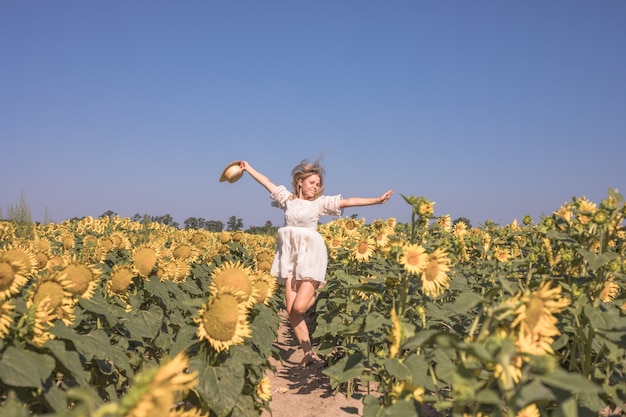 Belleza mujer iluminada por el sol en el campo de girasol amarillo Concepto de libertad y felicidad Niña feliz al aire libre