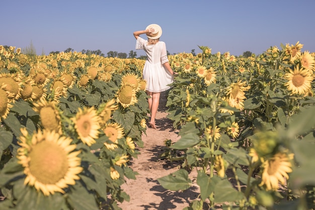 Belleza mujer iluminada por el sol en el campo de girasol amarillo Concepto de libertad y felicidad Niña feliz al aire libre