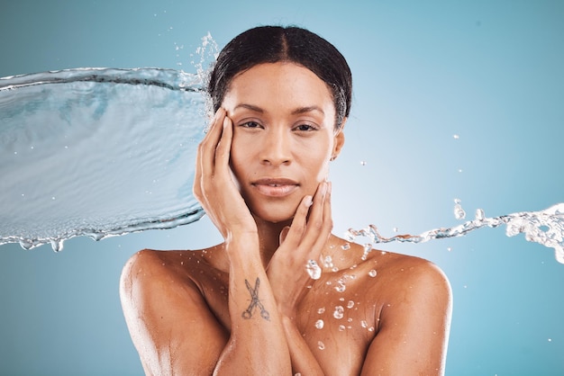 Belleza de mujer y salpicaduras de agua en hidratación para el cuidado de la piel para una higiene limpia o cosméticos contra un fondo de estudio azul Retrato de modelo femenino en hidratación o limpieza de lujo para un tratamiento perfecto de la piel