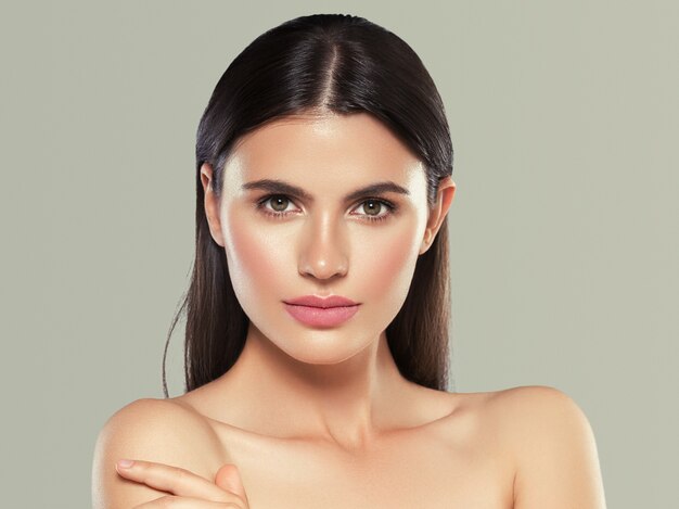 Belleza piel mujer cara piel sana hermosa modelo cerrar cara maquillaje natural cabello morena. Fondo de color. Tiro del estudio.