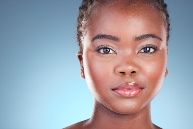 Belleza y retrato de mujer negra con maquillaje cosmético y tratamiento dermatológico Cara modelo de estudio y mujer africana con cuidado de la piel facial y fondo azul con brillo y cuidado de la piel