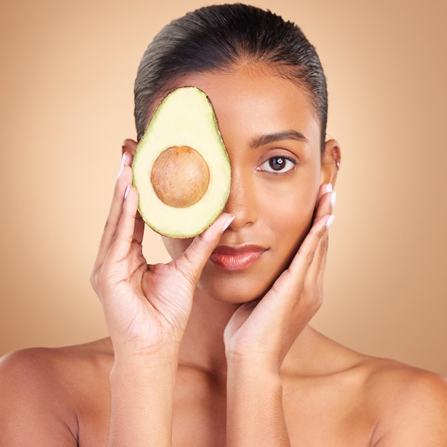 Belleza y rostro de mujer con aguacate y cuidado de la piel natural en retrato facial y maquillaje en el fondo del estudio Cuidado cosmético vegano y producto de la naturaleza orgánico y femenino con manos y brillo