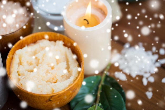 belleza, spa, cuidado corporal, cosmética natural y concepto de bienestar: exfoliación corporal y velas en madera sobre nieve