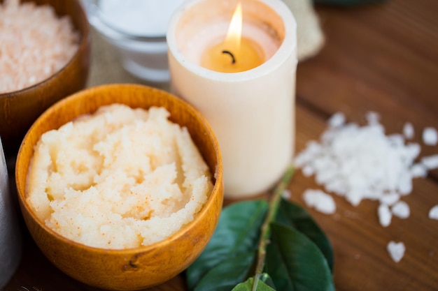 belleza, spa, terapia, cosmética natural y concepto de bienestar: cierre de exfoliación corporal y velas en madera