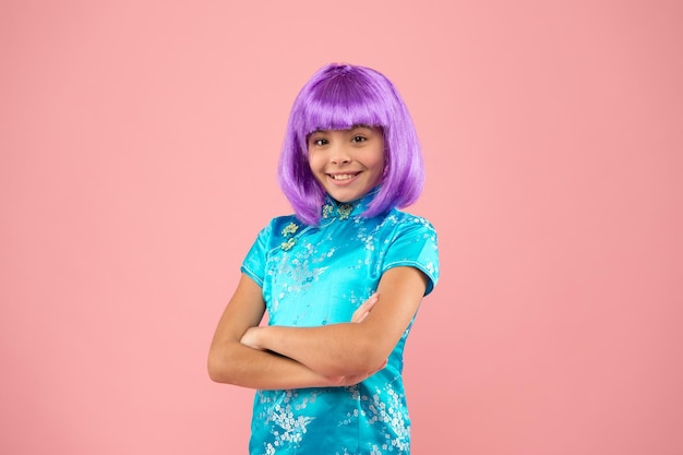 La belleza tiene que ver con ella Niño feliz usar peluca de pelo violeta fondo rosa Aspecto de belleza de modelo de moda pequeña Salón de belleza Moda y belleza