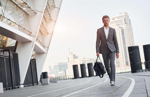 Belleza urbana Joven hombre de negocios con ropa formal gris está al aire libre en la ciudad