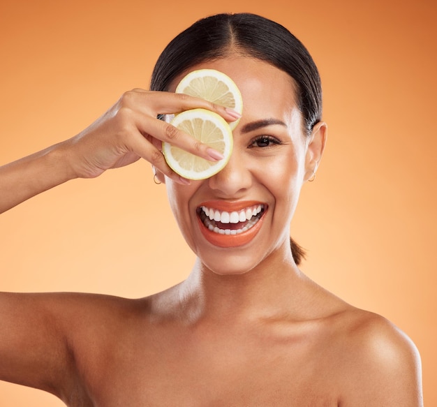 Belleza de vitamina c y cuidado de la piel de una mujer con una sonrisa sosteniendo fruta en la cara contra un fondo de estudio Retrato de modelo femenino feliz en cítricos saludables para la piel y el cuidado dental con dientes