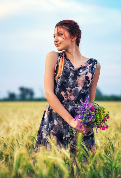 Bellezas al aire libre disfrutando de la naturaleza. Hermosa chica modelo adolescente en vestido con flores en el campo de primavera