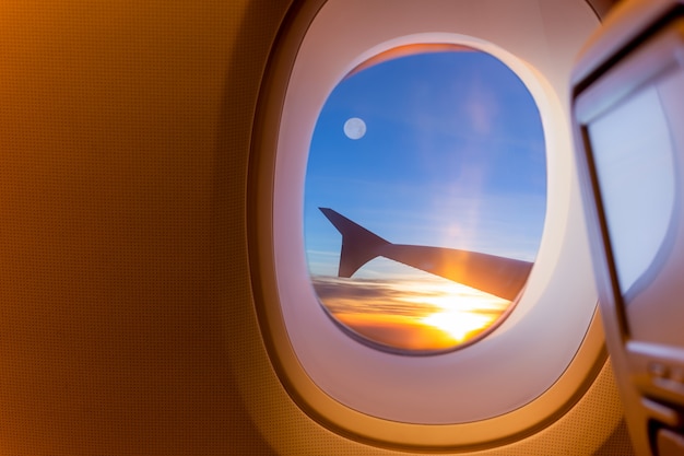 Bello paisaje de amanecer y luna llena a través de la ventana del avión.