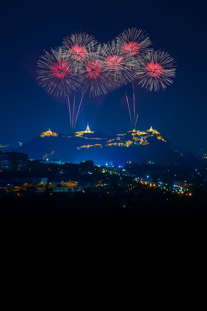 Bellos fuegos artificiales rojos en la noche con el templo en la vista a la montaña