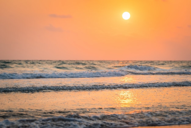 Foto belo amanhecer com pôr do sol e bela praia, onda suave e clara sobre a praia arenosa