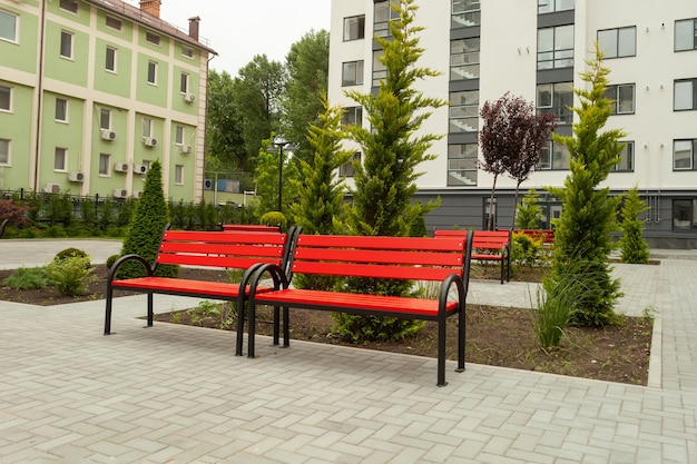 Belo banco vermelho de madeira no pátio de um novo edifício residencial