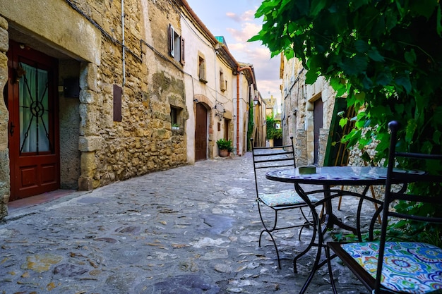 Belo beco cheio de casas de pedra e mesa e cadeiras de ferro para descansar Peratallada Girona Espanha