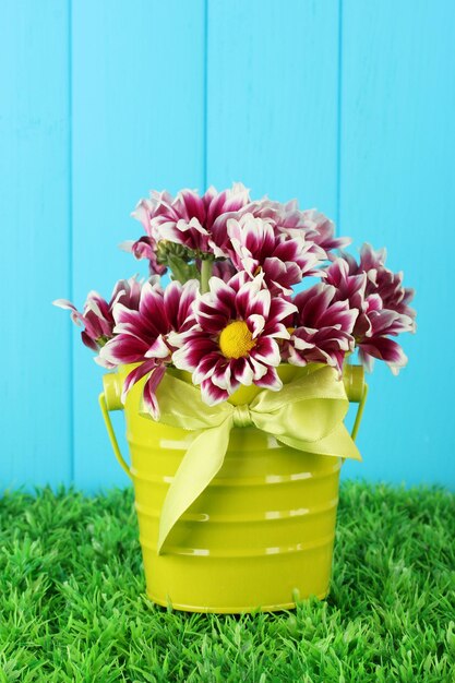 Foto belo bouquet de crisântemos em um balde colorido brilhante em fundo de cerca azul