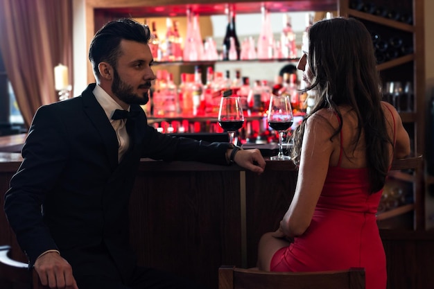 Belo casal de amantes flertando no pub e bebendo vinho tinto