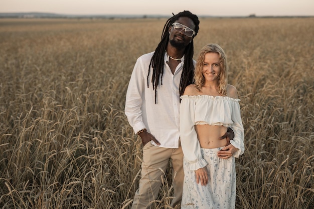 Foto belo casal de um homem africano e uma mulher caucasiana em uma caminhada no campo