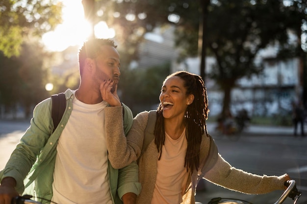 Foto belo casal feliz aluga bicicletas na cidade ri e brinca ao pôr do sol