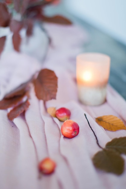 Belo cenário de mesa com folhas de outono, maçãs e velas Decorações de outono aconchegantes em um corredor de tecido rosa
