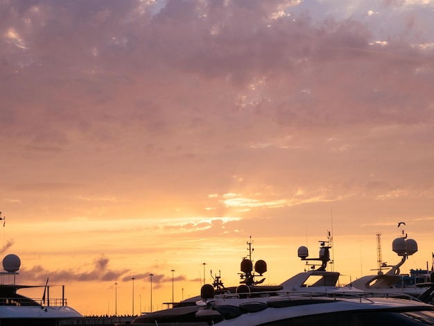 Belo céu dramático ao pôr do sol nas silhuetas do porto marítimo dos telhados dos iates