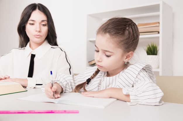 Belo conceito de família. mãe e filha sentadas juntas e estudando em casa.