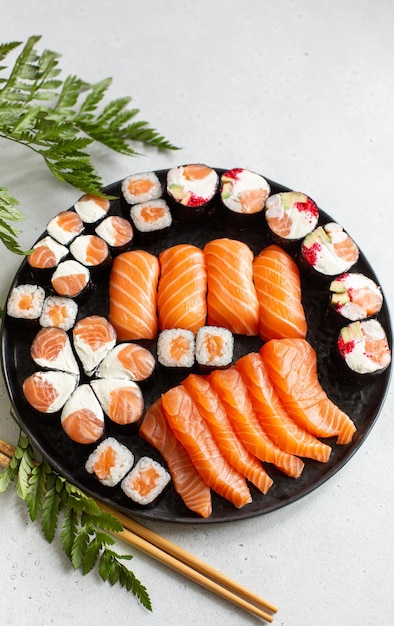 Foto belo conjunto festivo de rolos de sushi e salmão em uma placa preta é mostrado de cima