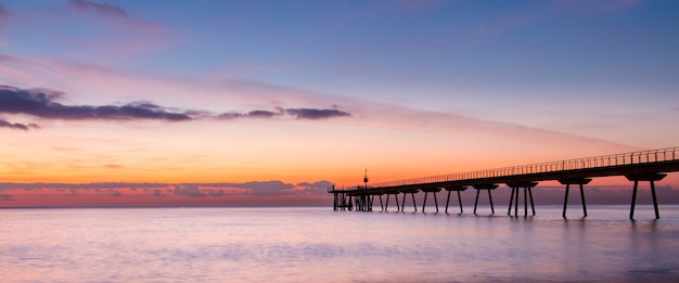 Foto belo despertar do céu com poucas nuvens e mar próximo a uma passarela