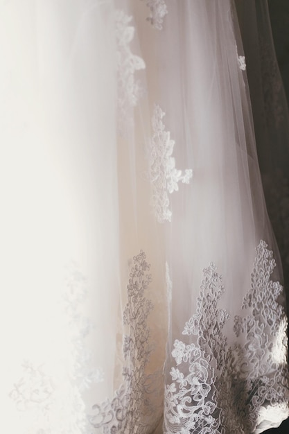 Belo detalhe floral no ornamento de renda do vestido de noiva de seda nos preparativos matinais nupciais do vestido branco