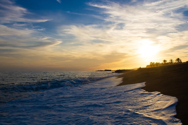 Belo e colorido pôr do sol luz quente e muitas nuvens ondas do mar na costa do mar