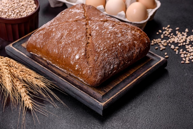 Belo e saboroso pão marrom em forma de quadrado em um fundo escuro de concreto Assando pão em casa