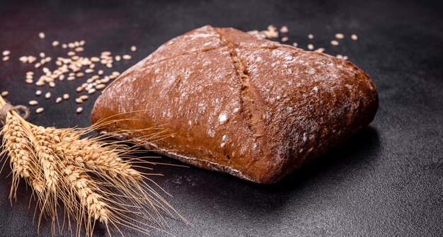 Belo e saboroso pão marrom em forma de quadrado em um fundo escuro de concreto Assando pão em casa