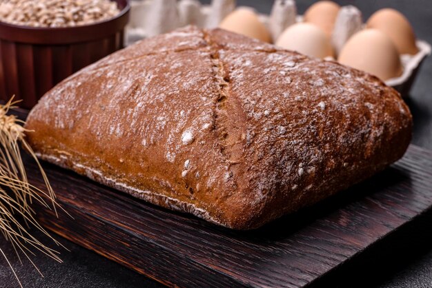 Belo e saboroso pão marrom em forma de quadrado em um fundo escuro de concreto