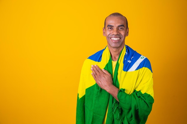 Belo homem afro brasileiro fã brasileiro copa do mundo 2022 mão no peito cantando o hino nacional música brasileira amada pátria patriota