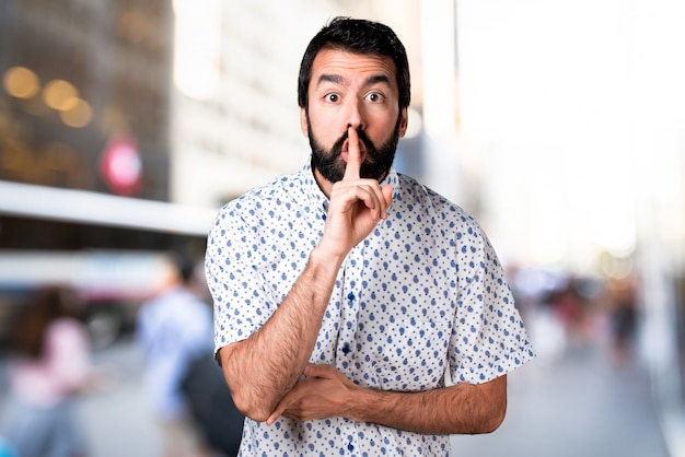 Belo homem moreno com barba fazendo gesto de silêncio