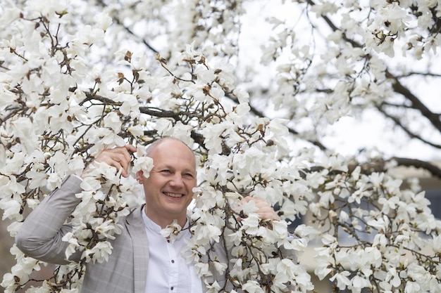 Belo homem sorridente no fundo da magnólia floração branca