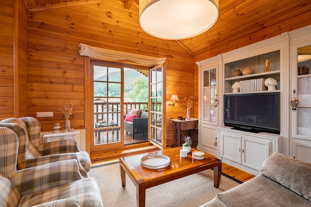 Foto belo interior de uma sala de estar aconchegante com vista para o terraço em uma casa de madeira vida em uma aldeia