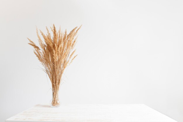 Belo interior em mesa de madeira branca de estilo escandinavo com um buquê de flores secas contra