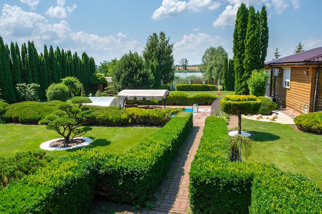 Belo jardim nas traseiras com árvores, arbustos e pedras bem aparadas. Projeto paisagístico. Foto de alta qualidade