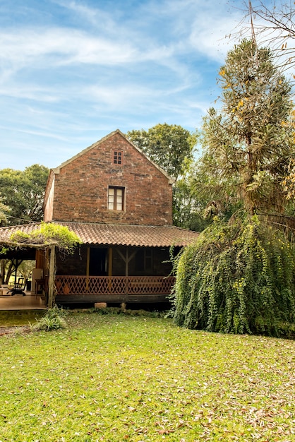 Belo jardim verde com folhas secas caídas na tarde ensolarada. Antiga casa de tijolos.