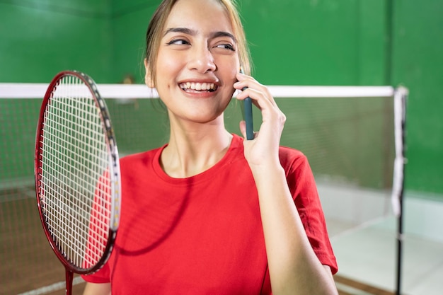 Belo jogador de badminton fazendo uma ligação com um smartphone