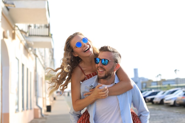 Belo jovem casal apaixonado, caminhando ao ar livre na rua da cidade, se abraçando.