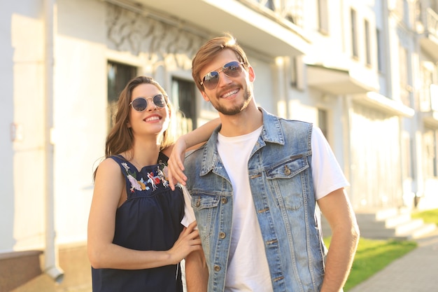 Belo jovem casal apaixonado, caminhando ao ar livre na rua da cidade, se abraçando.