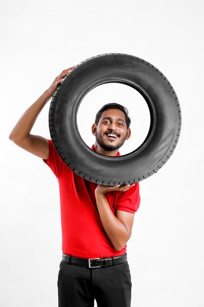 Foto belo jovem mecânico masculino com pneus novos, isolados no fundo branco.