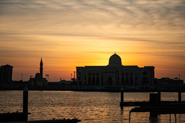 Foto belo nascer do sol no mar em sharjah belos edifícios de arquitetura árabe no fundo de um pôr-do-sol à noite