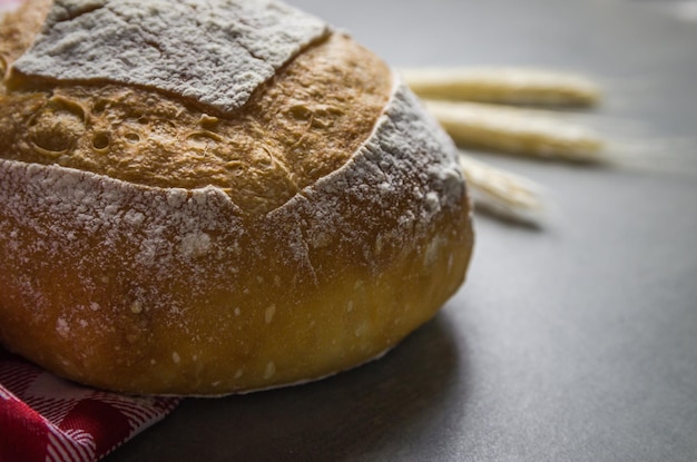 Belo pão de fermento em fundo cinza com flor de trigo seca