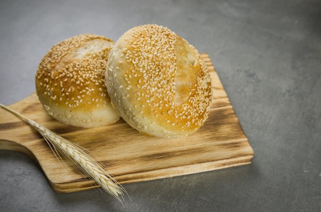 Belo pão de fermento em fundo cinza com flor de trigo seca