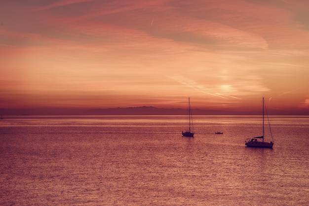 Belo pôr do sol colorido no mar com dois barcos à vela Fundo de viagem natural ao ar livre do mundo da beleza